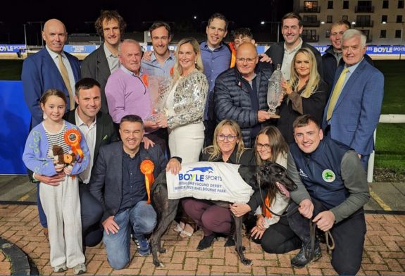 2025 BOYLE Sports Irish Greyhound Derby champion Cheap Sandwiches pictured with proud owners the Bark Wahlberg Syndicate, trainer Grahan Holland and family and connections. Kerry Boyle presents owner Dan Brassil and Claire Boyle presents trainer Graham Holland with GRI CEO Tim Lucey and Chairman Pat Flanagan also included in the photo at Shelbourne Park. Image shows the winning presentation at the 2025 BOYLE Sports irish Greyhound Derby FInal in Shelbourne Park with the winning greyhound Cheap Sandwiches in front of a group of people