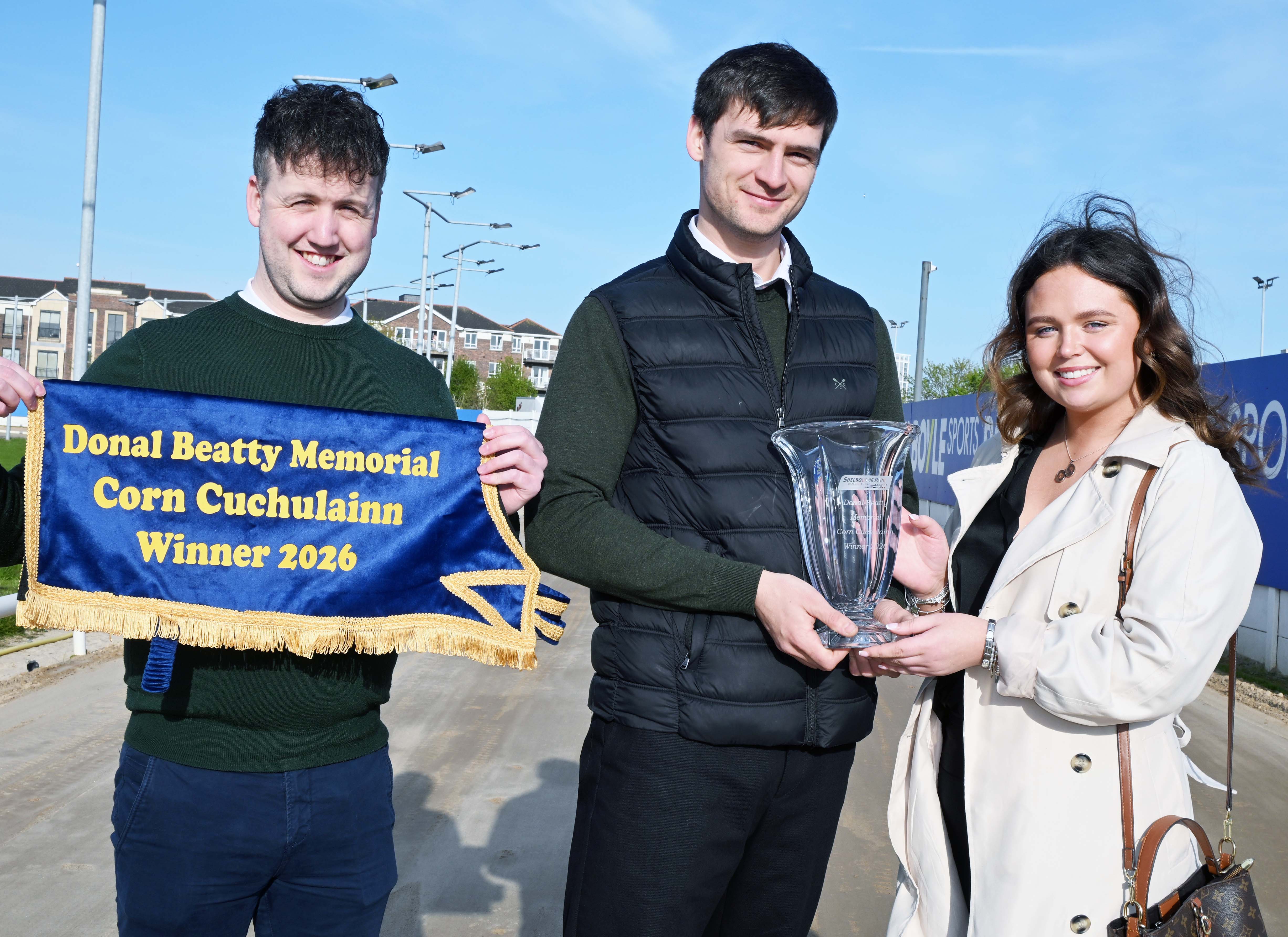 This is an image of three people. On the right is Emma Beatty, sponsor of the Donal Beatty Memorial Corn Cú Chulainn, presents the winner’s trophy to Eoin McCann, Section Manager at GRI. Pictured on the left is Dylan Brennan, Racing Manager, holding the presentation sheet.